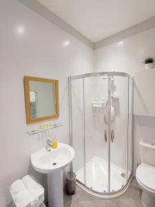 a white bathroom with a shower and a sink at Portrush by the Sea - 3 West Beach in Portrush
