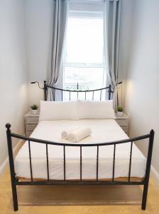 a bed with a black frame and a window at Portrush by the Sea - 3 West Beach in Portrush