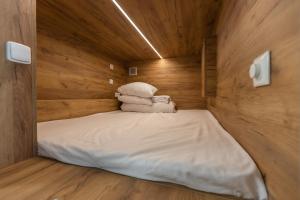 Cama pequeña en habitación de madera con toallas en Expo capsule Hostel, en Praga