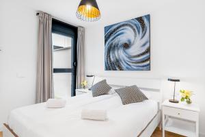 biała sypialnia z 2 łóżkami i obrazem na ścianie w obiekcie MEDANO4YOU Bogi's Holiday Home w mieście El Médano