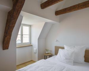 a bedroom with white walls and a bed with white pillows at Küchlinhaus in Memmingen