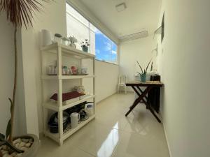 una sala de estar con un estante blanco y una mesa en Apartamento Acolhedor e Bem Localizado en Vila Velha