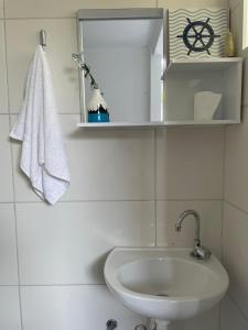 a white bathroom with a sink and a mirror at Apartamento Acolhedor e Bem Localizado in Vila Velha