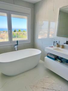 Baño blanco con bañera grande y lavamanos en Marbella Villa Sea View 10 Bedrooms, en Estepona