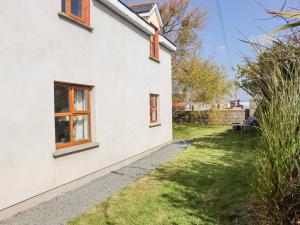 a white house with orange windows and a yard at Wheatfield Lodge in Fethard on Sea