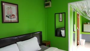 Dormitorio verde con cama y pared verde en ชมวิว รีสอร์ท, en Loei