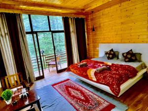 a bedroom with a large bed with a red comforter at WildWoodHome Jibhi in Jibhi