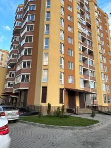 - un grand immeuble avec des voitures garées devant dans l'établissement Красиві апартаменти, à Ternopil