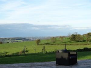 a chair sitting on a porch with a view of a field at Couleur Campagne in Theux