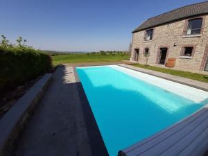 a large blue swimming pool next to a building at Couleur Campagne in Theux