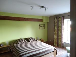 a bedroom with a large bed with green walls at Couleur Campagne in Theux