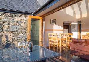 a patio with a glass table and a stone wall at Beudyr Gelli in Trawsfynydd