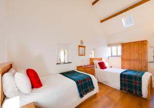 a bedroom with two beds with red and green sheets at Beudyr Gelli in Trawsfynydd