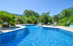 Beautiful Home In Petreto Bicchisano With Heated Swimming Pool في Petreto-Bicchisano: مسبح ازرق وكراسي واشجار