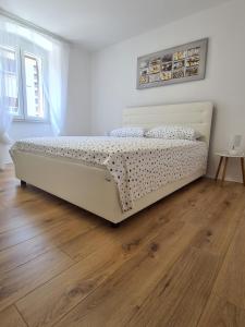 Cama blanca en habitación con suelo de madera en Apartment Andy, en Rijeka