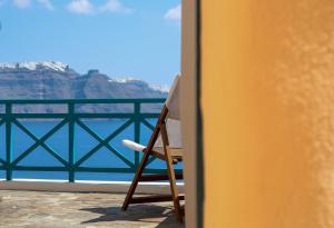 a chair sitting on a balcony overlooking the water at Oia VineyART Homes in Oia