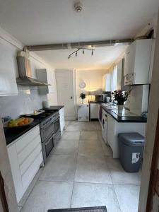 cocina grande con armarios y electrodomésticos blancos en Luton Town House Near AIRPORT en Luton
