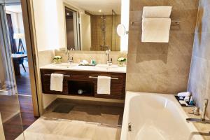ein Badezimmer mit einer Badewanne, einem Waschbecken und einem Spiegel in der Unterkunft Steigenberger Hotel Köln in Köln