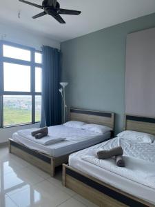 two beds in a bedroom with a ceiling fan at Atlantis Sea View Unit in Malacca