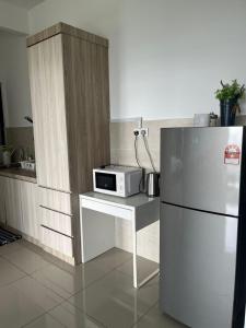 a kitchen with a refrigerator and a table with a microwave at Atlantis Sea View Unit in Malacca