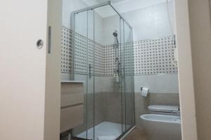 La salle de bains est pourvue d'une douche en verre, de toilettes et d'un lavabo. dans l'établissement Villanova Apartment, à Cagliari