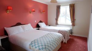 2 Betten in einem Hotelzimmer mit roten Wänden in der Unterkunft Kilmurvey House in Kilronan