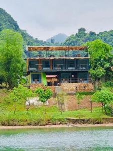 ein Haus auf einem Hügel neben dem Wasser in der Unterkunft Phong Nha A Little Leaf Homestay in Phong Nha