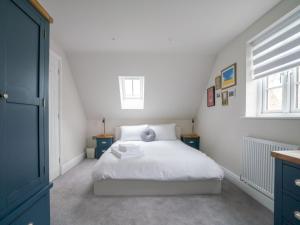 sypialnia z białym łóżkiem i 2 oknami w obiekcie Pass the Keys Town Centre cottage with garden and parking w mieście Cheltenham