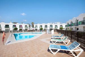 ein Swimmingpool mit Liegestühlen neben einem Gebäude in der Unterkunft Dunes resort to relax Wifi in Corralejo