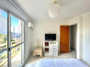 Schlafzimmer mit einem Bett, einem TV und einem Fenster in der Unterkunft Departamento RIOJA in Paraná