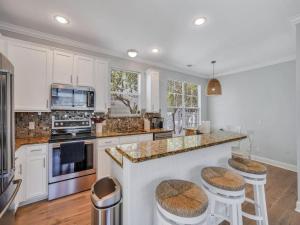 a kitchen with white cabinets and a island with bar stools at Coastal Quarters in Bluffton