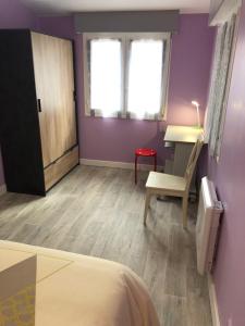 een slaapkamer met paarse muren, een stoel en een bureau bij Le Refuge d'Helix in Viviez