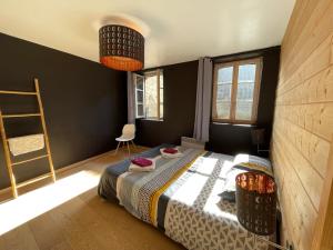 a bedroom with a bed and a ladder and windows at Appartement au coeur d'Arbois in Arbois