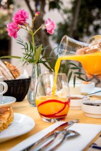 une personne versant du jus d'orange dans un verre sur une table dans l'établissement Le Vieux Logis Chambres d'Hôtes, à La Farlède