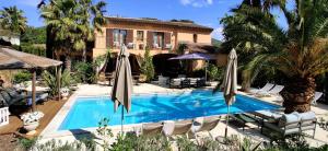 a swimming pool with chairs and umbrellas in front of a house at Maison Prestige Saint Tropez by Roberto Geissini in Grimaud