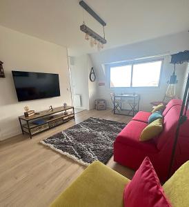 a living room with a red couch and a flat screen tv at Les Marines - Belle Vue Mer in Cabourg
