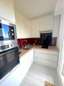 kuchnia z białymi szafkami i kuchenką mikrofalową w obiekcie Studio Les Marines - Belle Vue Mer w mieście Cabourg +1 zdjęcie
