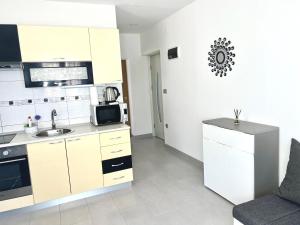 a white kitchen with a sink and a microwave at Apartman Solin 3, parking in Solin