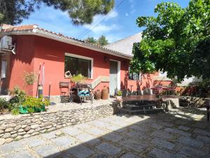 una casa roja con un patio de piedra frente a ella en Casita de invitados cerca de Madrid, en Moralzarzal