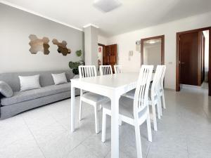un comedor blanco con una mesa y sillas blancas en Apartamentos Xulia, en Raxó