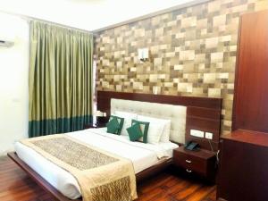 een slaapkamer met een groot bed met groene kussens bij Hotel Amisa Golf Course Road MG Road in Gurgaon