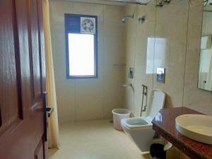 ein Bad mit einem Waschbecken, einem WC und einem Fenster in der Unterkunft Hotel Amisa Golf Course Road MG Road in Gurgaon