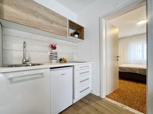 una cucina bianca con lavandino e una camera da letto di Apartments Valerian a Novigrad Istria