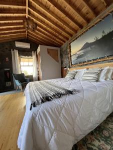 uma grande cama branca num quarto com tecto em madeira em Pico Formoso Vínea Lava Alojamentos Pico em Prainha de Baixo