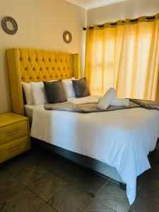 a bedroom with a large bed with a yellow curtain at Aaron’s apartments in Ladysmith