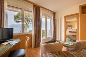 uma sala de estar com televisão e uma grande janela em Bellavista Swiss Quality Hotel em Vira