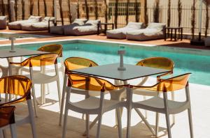 een tafel en stoelen naast een zwembad bij Regency Boutique Hotel Holiday Suites in Paphos City