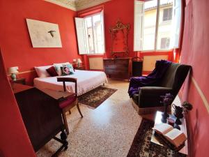 1 dormitorio con paredes rojas, 1 cama y 1 silla en Casa degli Artisti, en Citerna