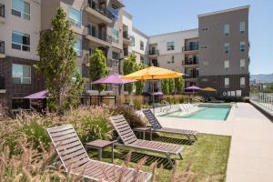 um grupo de cadeiras e guarda-sóis ao lado de uma piscina em Downtown Walking Oasis with King BD and City View em Salt Lake City