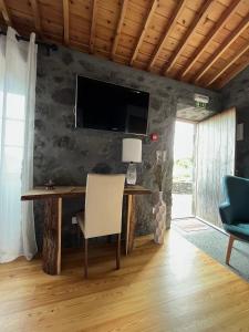 uma secretária com uma cadeira e uma televisão na parede em Pico Formoso Vínea Lava Alojamentos Pico em Prainha de Baixo